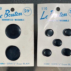 Puede incluir: Dos tarjetas de botones negros. Una tarjeta tiene dos botones, cada uno de 22 mm de diámetro. La otra tarjeta tiene cinco botones, cada uno de 11 mm de diámetro. Las tarjetas están etiquetadas como "Le Bouton" y "Guaranteed Washable."