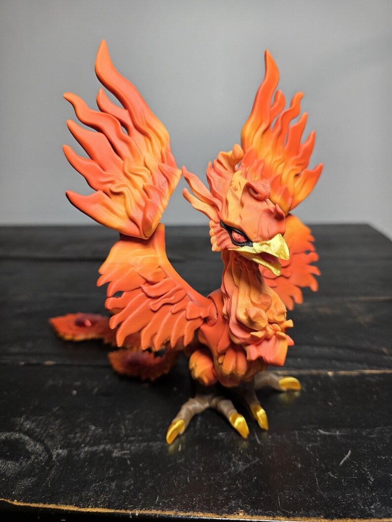May include: A detailed figurine of a phoenix, featuring vibrant orange and yellow hues. The bird's wings are spread, showcasing intricate feather details. The beak and talons are accented with gold, creating a striking contrast.