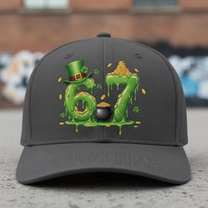 May include: A grey baseball cap with a green, dripping design of the numbers "67", a leprechaun's hat, a pot of gold, and scattered gold coins. The design is themed around St. Patrick's Day.