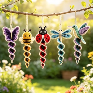 May include: Five hanging crochet ornaments featuring a purple butterfly, a yellow and black bee, a red ladybug, a blue dragonfly, and a green and purple hummingbird. Each creature is attached to a spiraling, multi-colored yarn tail.