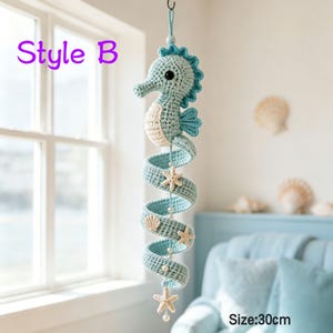 May include: A hanging crochet seahorse mobile in light blue and cream, featuring a spiral tail adorned with small white beads and cream-colored starfish accents. The text Style B and Size: 30cm are visible on the image, indicating the product length.