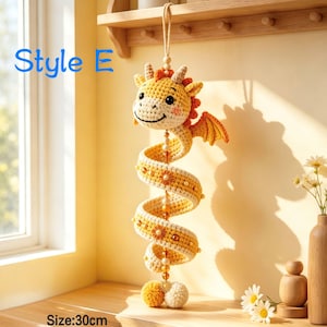 K&ouml;nnte beinhalten: Ein h&auml;ngendes H&auml;kel-Drachenornament in Gelb und Creme mit orangefarbenen Akzenten, einem spiralf&ouml;rmigen K&ouml;rper, kleinen Fl&uuml;geln und einer zentralen Perlenschnur. Der Text 'Style E' und 'Size:30cm' ist sichtbar. Der Drache hat ein l&auml;chelndes Gesicht.
