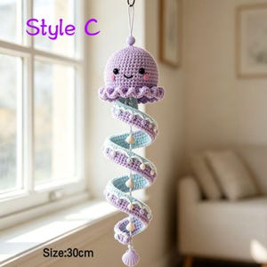 May include: A lavender crochet jellyfish hanging decoration labeled Style C with a size of 30cm. The jellyfish has a round head with black eyes and pink cheeks, and a long spiral tentacle featuring light blue accents, small beads, and shells.