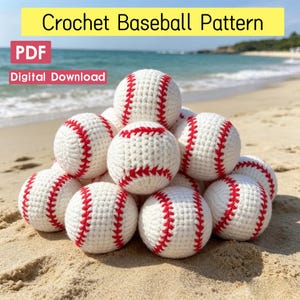 May include: A pile of white crocheted baseballs with red stitching. The text "Crochet Baseball Pattern", "PDF", and "Digital Download" is visible. The baseballs are arranged in a pyramid shape on a sandy beach with the ocean in the background.