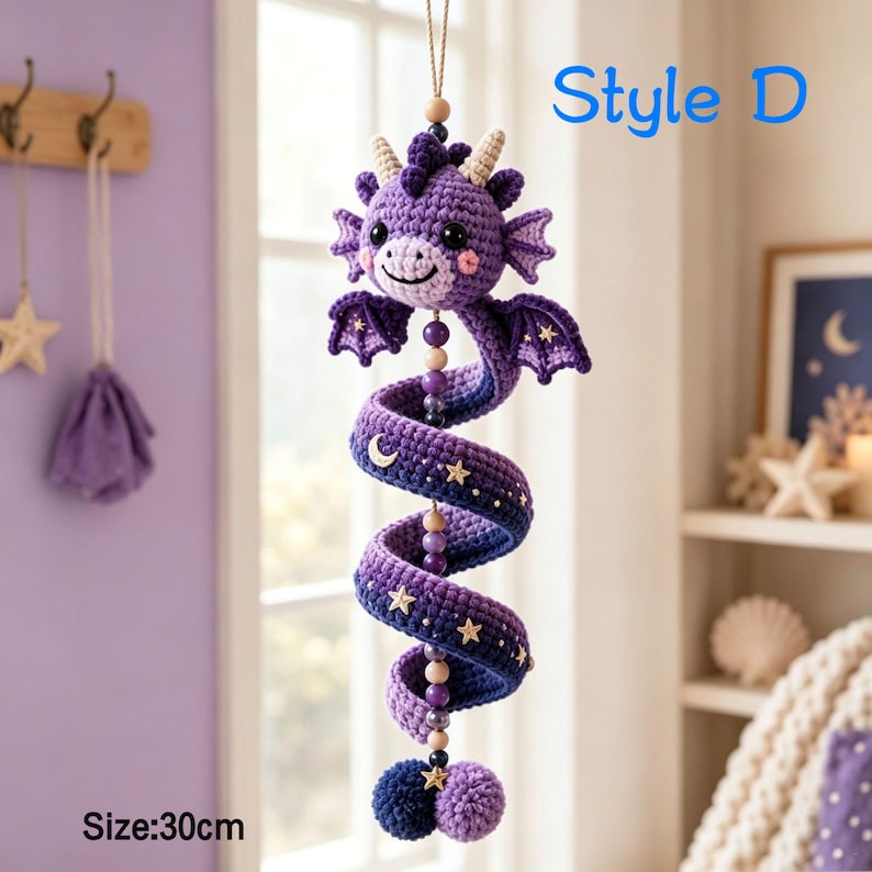 K&ouml;nnte beinhalten: Ein violettes H&auml;kel-Drachen-H&auml;ngedekor mit spiralf&ouml;rmigem K&ouml;rper, verziert mit kleinen Stern- und Mondakzenten, Holzperlen und einem Bommelschwanz. Der Drache hat zwei Fl&uuml;gel, H&ouml;rner und schwarze Augen. Text Style D und Size: 30cm sind sichtbar.