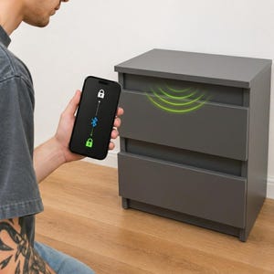 Puede incluir: Una mesita de noche gris con tres cajones. Un smartphone muestra un icono de candado, un símbolo de Bluetooth y un icono de desbloqueo. Ondas verdes emanan de la mesita de noche, sugiriendo integración domótica.