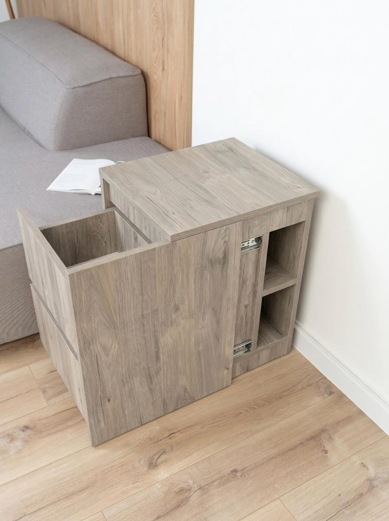 May include: A light brown wood-grain side table featuring a rectangular top, a pull-out storage compartment with a deep interior, and two open side shelves. The unit includes visible metal drawer slides on the side of the main storage section.