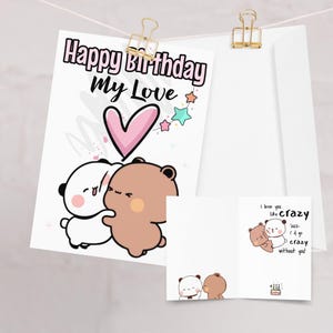 May include: A birthday greeting card with the text "Happy Birthday My Love" and a cartoon illustration of two hugging bears. The card includes a pink heart and colorful stars. An additional card reads "I love you like crazy".