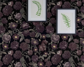 Puede incluir: Papel pintado con un denso patrón floral de rosas de color morado oscuro y negro con hojas verdes sobre un fondo negro. Dos láminas botánicas enmarcadas de hojas de helecho verdes cuelgan en la pared. Un banco azul con una manta de piel sintética marrón se sitúa debajo.