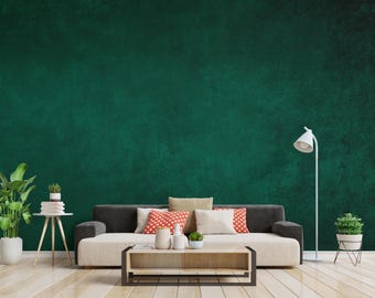 Può includere: Un moderno soggiorno con una parete strutturata verde scuro. Un divano beige con braccioli grigio scuro è adornato da cuscini in vari colori e motivi. Un tavolino in legno, una lampada da terra bianca e piante in vaso completano la scena.