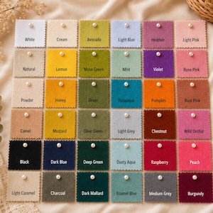 May include: A grid of thirty square fabric swatches in various colors, each featuring a small white pearl bead in the center. The swatches are labeled with names including White, Cream, Avocado, Light Blue, Heather, Lemon, Moss Green, and others.