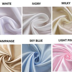 Op de afbeelding: Close-up van zes stoffen stalen in verschillende kleuren. De kleuren zijn wit, ivoor, melkachtig, champagne, hemelsblauw en lichtroze. De stof lijkt een gladde, glanzende satijn te zijn.