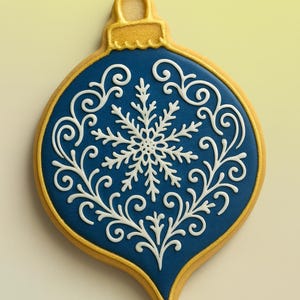 May include: A blue Christmas bauble biscuit with a gold border and top. The biscuit is decorated with white icing in a snowflake and scroll design. The bauble shape is a classic teardrop.