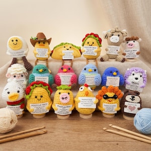 May include: A selection of brightly coloured, crocheted animal and food-themed figures, such as an egg, taco, and cow. Each figure has a smiling face and a small sign with positive messages. Crochet hooks and yarn are in the foreground.
