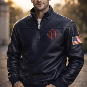 May include: A navy blue leather jacket with a quarter-zip closure, featuring a red embroidered emblem and an American flag patch on the sleeve. The jacket has a ribbed cuff and a stand-up collar.