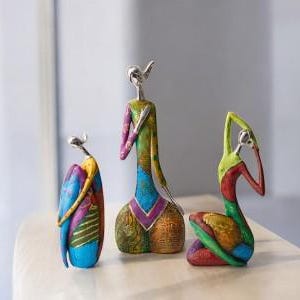 May include: Three colourful abstract figurines made of painted resin. The figurines are in various poses and feature geometric patterns in shades of blue, green, yellow, red, and purple.