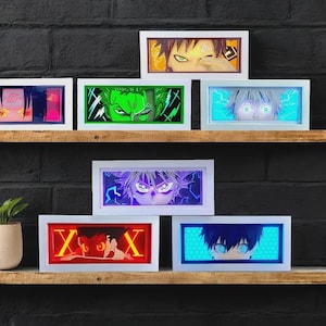 Peut inclure: Une collection de six boîtes lumineuses rectangulaires présentant des portraits de personnages d'anime illuminés. Chaque boîte à cadre blanc affiche un personnage unique avec un éclairage LED vibrant en rouge, bleu, vert et violet, montrant des expressions faciales détaillées.