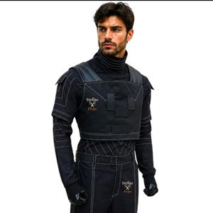 May include: Black costume with white stitching, featuring a high collar and a cropped vest with leather accents. The text "Stellar Props" is visible on the vest and pants. The outfit includes gloves and pants.