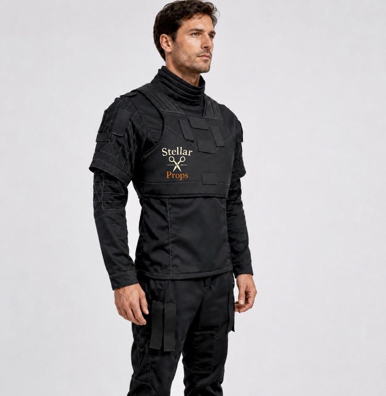 May include: A black tactical shirt featuring a high collar, short sleeves, and a structured chest panel with multiple rectangular patches. The chest displays the text Stellar Props with a scissors icon. The shirt includes reinforced stitching details.