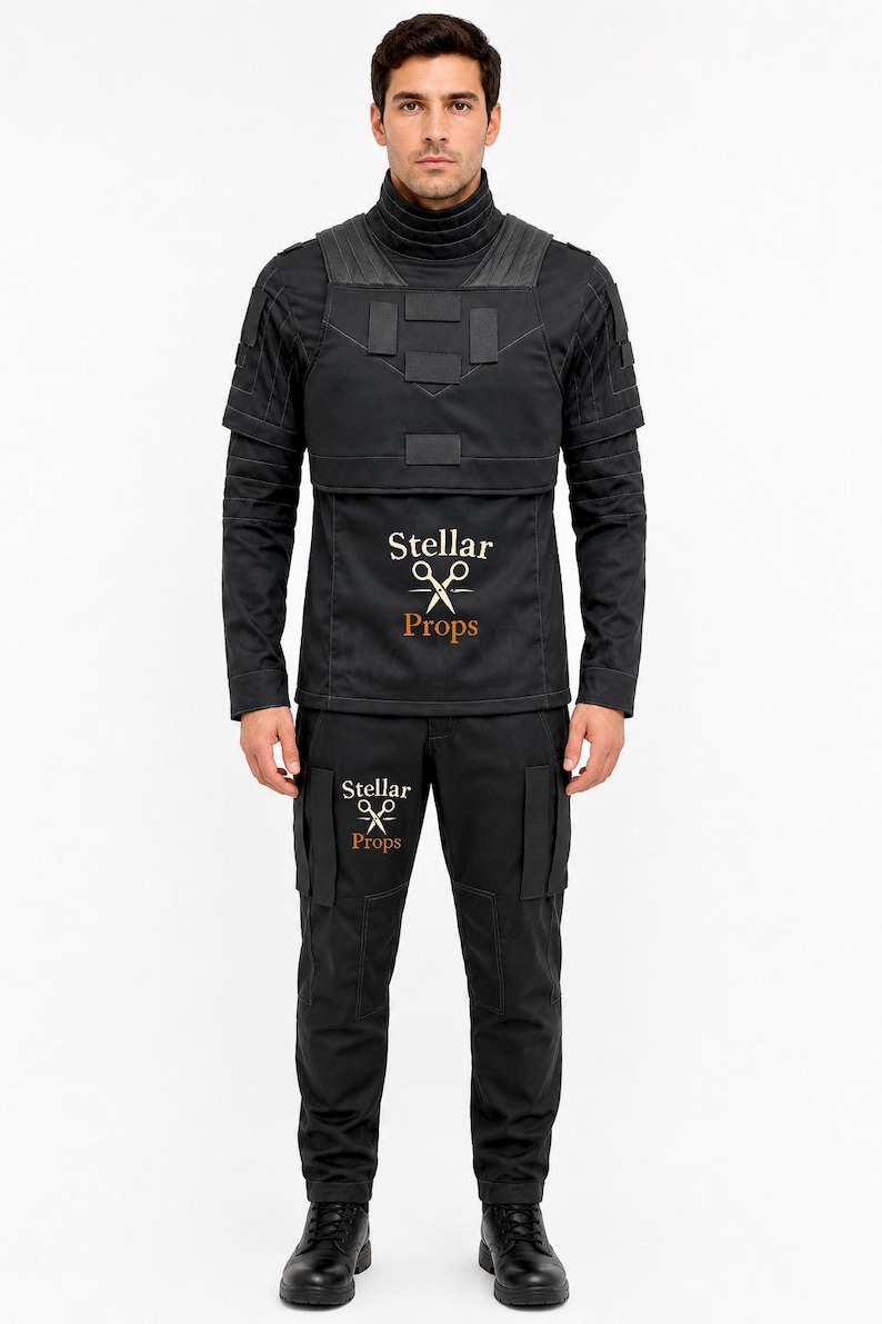 May include: A black tactical-style uniform consisting of a long-sleeved shirt with a high collar, a chest plate overlay, and matching trousers. The shirt and pants feature the text Stellar Props with a scissors icon printed in white and orange.