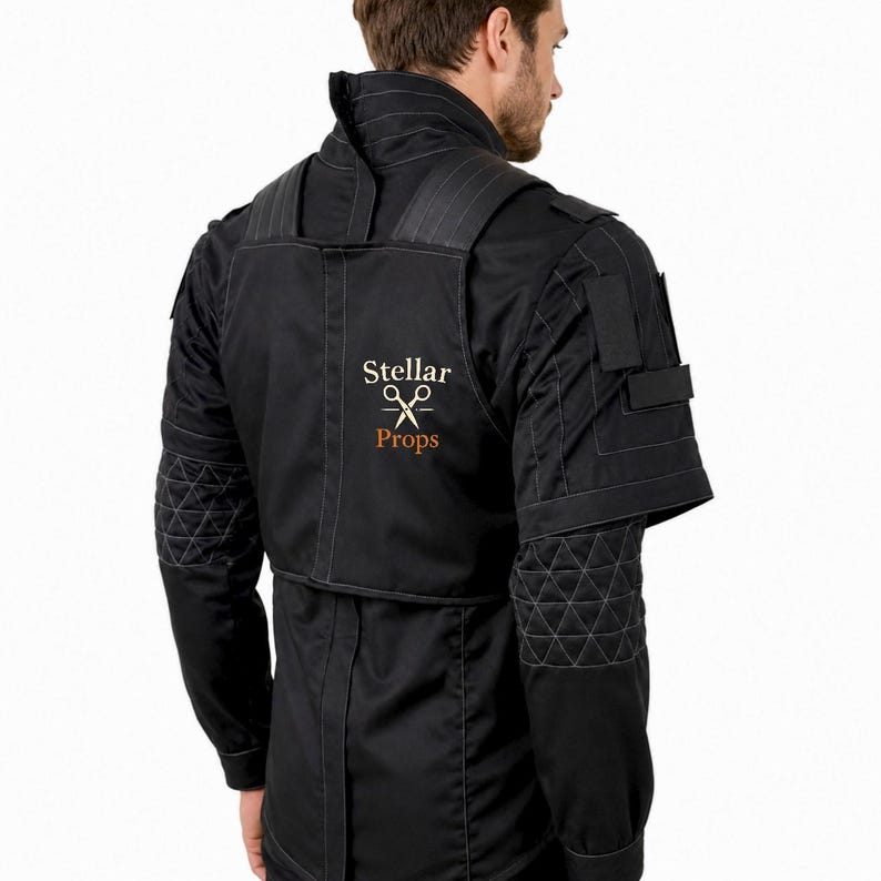 May include: A black tactical-style jacket featuring a high collar, quilted elbow patches, and shoulder straps. The back displays the embroidered text Stellar Props with a graphic of crossed scissors in white and brown thread on the upper panel.