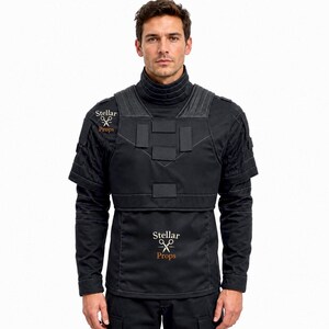 May include: A black tactical-style long-sleeve shirt featuring a high ribbed collar, a structured chest panel with rectangular patches, and short sleeves layered over long sleeves. The garment displays the text Stellar Props with scissors.