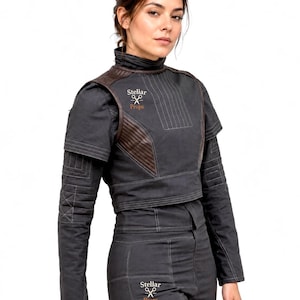 May include: A dark gray cropped jacket and matching pants set featuring brown quilted shoulder panels, a high collar, and visible stitching. The garment displays the text Stellar Props with a scissors icon on the chest and the upper thigh area.