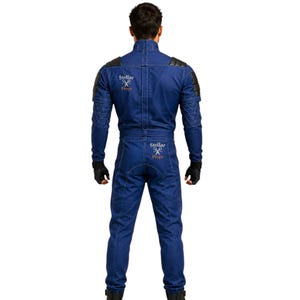 May include: Blue jumpsuit with black accents on the shoulders and sleeves. The back of the jumpsuit features the text "Stellar Props" in white. The jumpsuit has a high collar and is worn with black gloves.