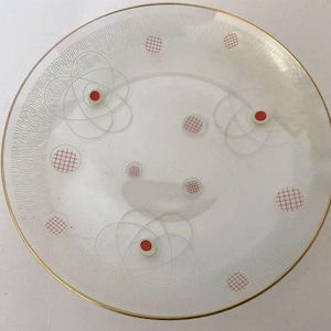 Könnte beinhalten: Eine Vintage-Deckenleuchte aus Glas mit goldenem Rand. Das klare Glas hat ein weißes, mattiertes Design mit roten Akzenten und einem Gittermuster. Die Leuchte hat eine moderne Ästhetik aus der Mitte des Jahrhunderts.