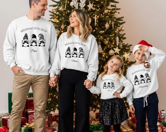 May include: A family of four wearing matching white sweatshirts with a black gnome design and the text "WEIHNACHTSCREW". The sweatshirts have the words "Papa", "Mama", "Susu", and "Maximilian" printed below the gnomes. A Christmas tree is in the background.