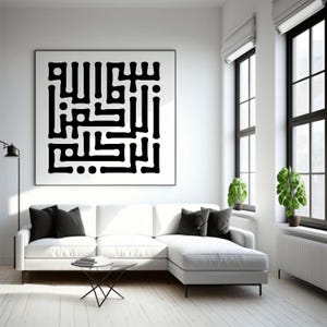 Op de afbeelding: Een groot, ingelijst zwart-wit kunstwerk met Arabische kalligrafie hangt boven een witte hoekbank. De woonkamer heeft een minimalistisch design met zwarte accenten, waaronder sierkussens en raamkozijnen. Groene planten voegen een vleugje kleur toe.