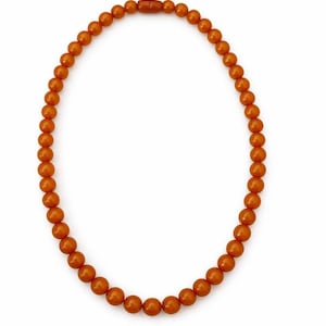 Puede incluir: Un collar compuesto por numerosas cuentas redondas de color ámbar. Las cuentas están ensartadas, formando un círculo completo. El collar se muestra sobre un fondo blanco, resaltando sus tonos cálidos y terrosos. El cierre es de color ámbar a juego.