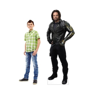 May include: A life-size cardboard cutout of a man in a black leather jacket and black pants, with a metallic arm. Next to him is a boy in a green plaid shirt and blue jeans. Both figures are standing on a white background.