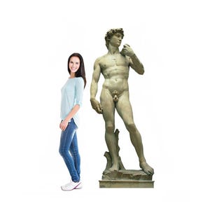 May include: A full-body image of the statue of David, a Renaissance masterpiece, stands tall. The statue is a nude male figure with a muscular build, standing on a stone base. A woman in a light blue top and jeans stands next to the statue.