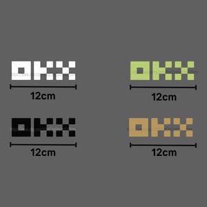 May include: Four stickers in white, green, black, and gold, each with a geometric design and the text "OKX". Each sticker is 12cm in length.