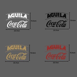 May include: Four logos featuring the text "AGUILA Coca-Cola" in white, black, gold, and red. Each logo measures 15.4 cm in height and 23.7 cm in width. The logos are set against a grey backdrop.
