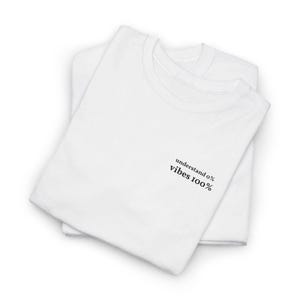 Könnte beinhalten: Zwei weiße T-Shirts übereinander gestapelt. Das obere T-Shirt hat den schwarzen Text "understand 0% vibes 100%" auf der Vorderseite.