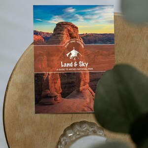 May include: A guide to Arches National Park, titled "Land & Sky," features a landscape photo with red rock formations and a sunset. The cover includes the text "Plan, Hike, Explore" and a silhouette of a hiker.