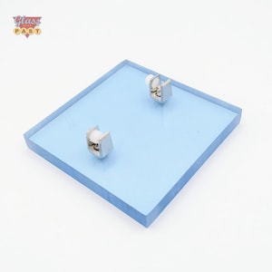 May include: A square, light blue glass panel with two silver-colored, roller-style hardware pieces attached. The panel has a beveled edge. The logo "Glass Past" is in the upper left corner.