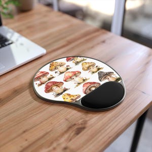 May include: A white mousepad with a whimsical design of colorful mushrooms. The mousepad has a black wrist rest.