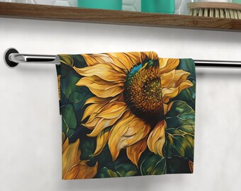 May include: A kitchen towel with a sunflower design. The sunflower is yellow with a brown center and green leaves. The towel is hanging on a towel rack.