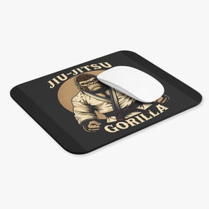 May include: A black mouse mat with a graphic of a gorilla wearing a white gi and a black belt. The text "Jiu-Jitsu Gorilla" is printed on the mouse mat.