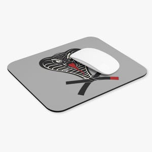 May include: A gray mouse pad with a black cobra graphic and crossed black belts. The cobra has a red tongue.