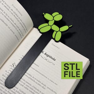 Op de afbeelding: Een zwarte bladwijzer met een getextureerd oppervlak, bekroond met een groen ballonhondontwerp. De bladwijzer is in een open boek geplaatst. De tekst "STL FILE" is zichtbaar op de pagina.