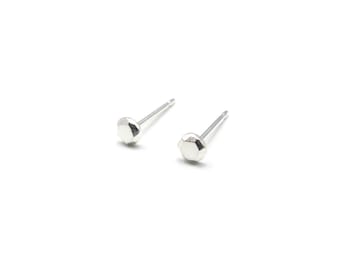 Könnte beinhalten: Ein Paar silberne Ohrstecker mit einem facettierten, geometrischen Design.