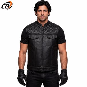 May include: A black leather vest featuring a quilted hexagonal pattern across the upper chest and shoulders. The garment includes a mandarin collar, a central front zipper closure, and two chest pockets with buttoned flaps over a black t-shirt.