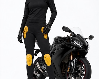 May include: Black long-sleeve mock neck shirt, black pants with yellow honeycomb-patterned hip and knee armor, black leather gloves, and black boots. A black sport motorcycle is positioned to the side of the protective riding gear.