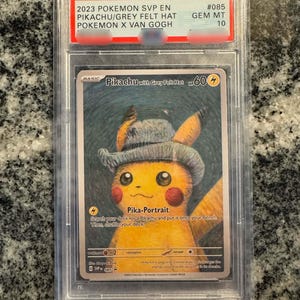 May include: A graded Pokémon card featuring Pikachu wearing a grey felt hat, a collaboration with Van Gogh. The card is encased in a protective case with a red and white label indicating its condition and grade.