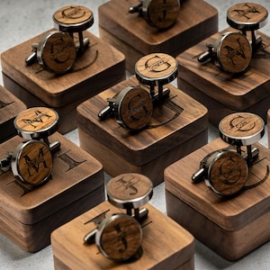 Può includere: Una collezione di gemelli in legno personalizzati con dettagli in metallo argentato, ognuno inciso con un nome o un'iniziale. I gemelli sono presentati in scatole di legno individuali, un regalo sofisticato e personalizzato.