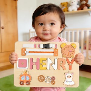 May include: A wooden educational puzzle board with the name "HENRY" spelled out in colourful letters. The board features a zipper, buckle, clock, and other interactive elements. A carriage, gears, and a llama are also included.